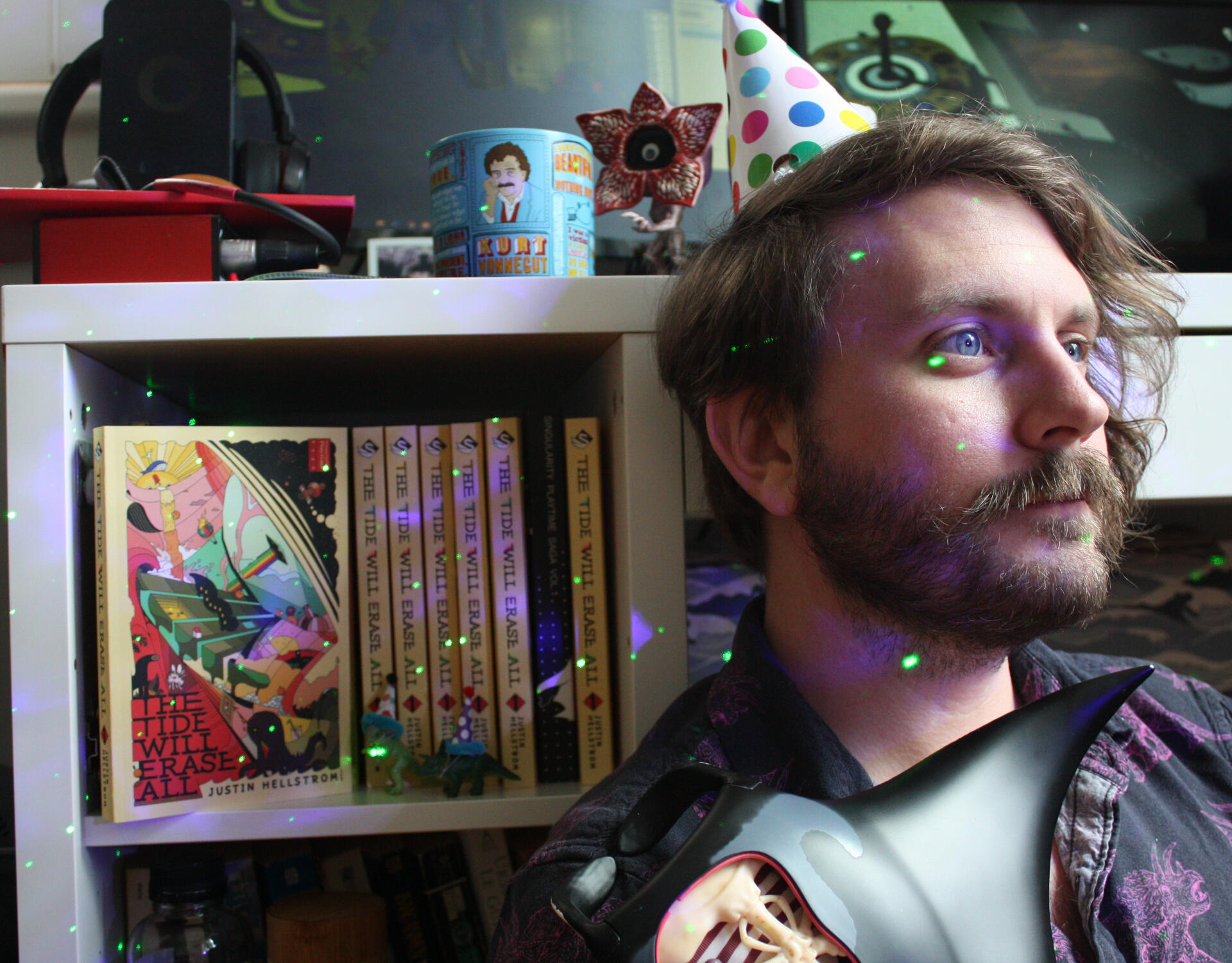 Author in a party hat holding a mantaray model by his novels